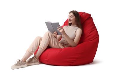 Beautiful young woman reading book on red bean bag chair against white background