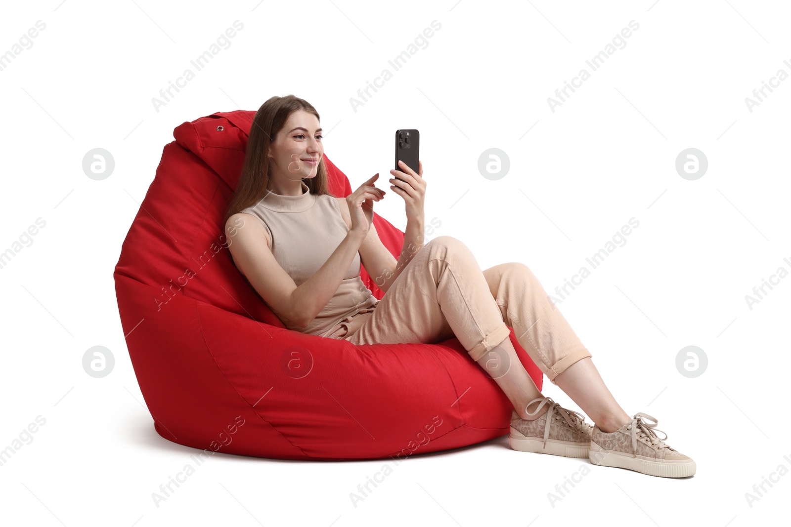 Photo of Beautiful young woman using smartphone on red bean bag chair against white background