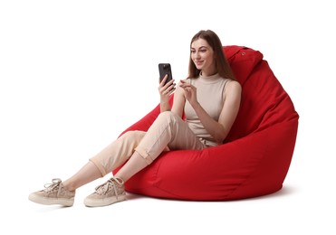 Beautiful young woman using smartphone on red bean bag chair against white background