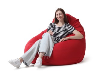 Smiling woman sitting on red bean bag chair against white background