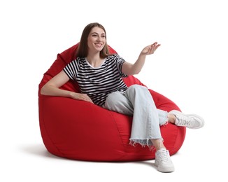 Smiling woman sitting on red bean bag chair against white background