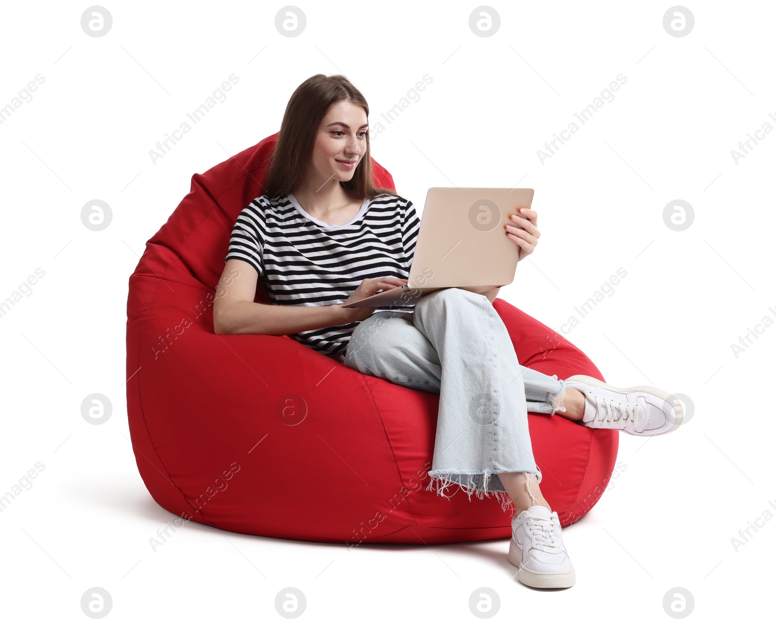 Photo of Beautiful young woman with laptop sitting on red bean bag chair against white background