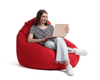 Beautiful young woman with laptop sitting on red bean bag chair against white background