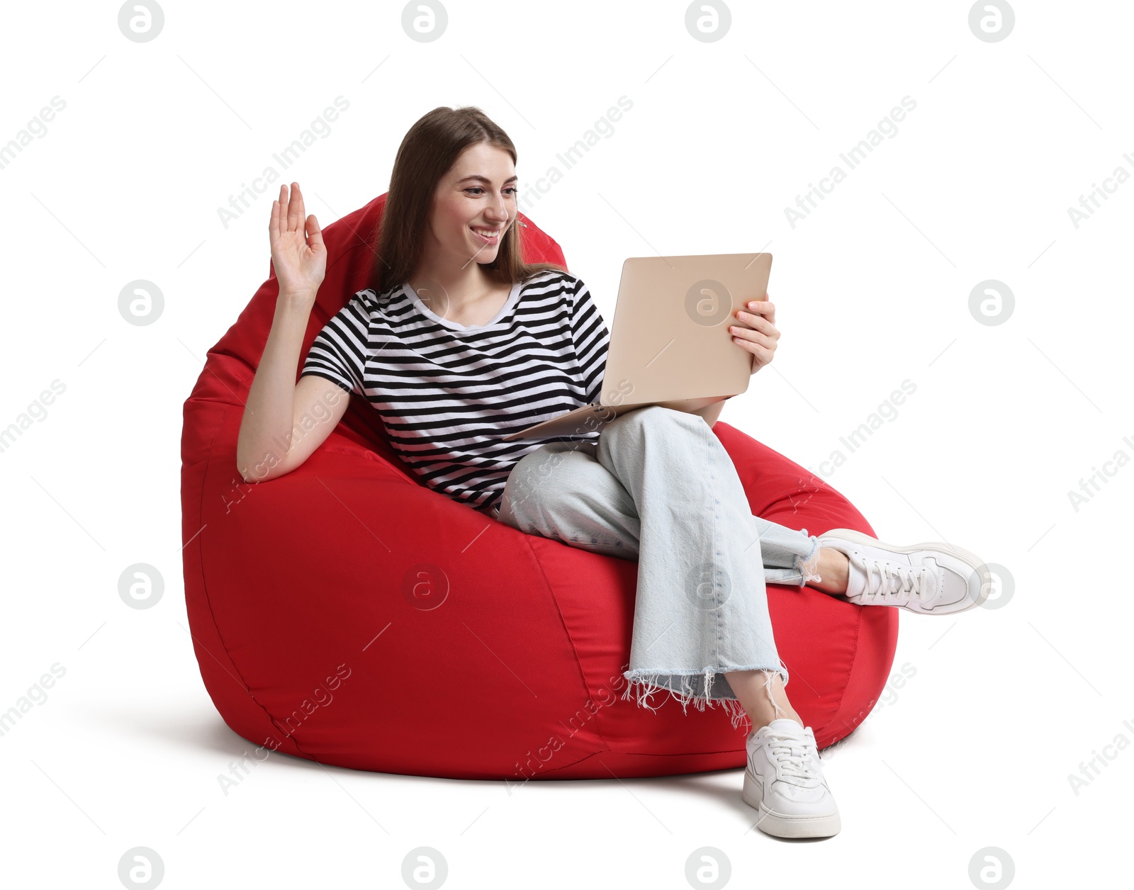 Photo of Smiling woman with laptop having online meeting while sitting on red bean bag chair against white background