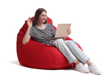 Photo of Smiling woman with laptop having online meeting while sitting on red bean bag chair against white background