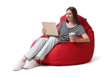 Smiling woman with laptop and cup of drink having online meeting while sitting on red bean bag chair against white background