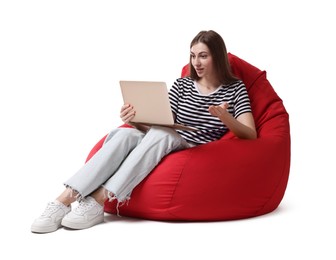 Emotional woman with laptop having online meeting while sitting on red bean bag chair against white background