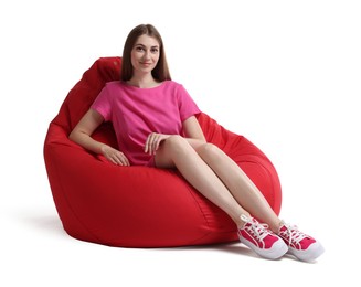 Beautiful young woman sitting on red bean bag chair against white background