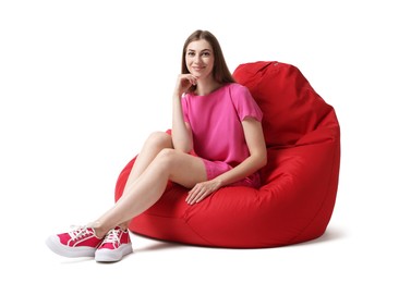 Beautiful young woman sitting on red bean bag chair against white background