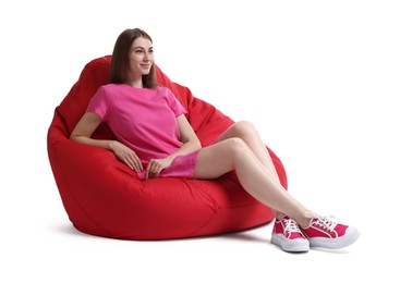 Beautiful young woman sitting on red bean bag chair against white background