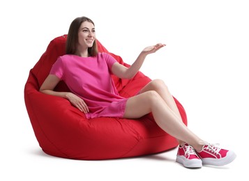 Smiling woman sitting on red bean bag chair against white background