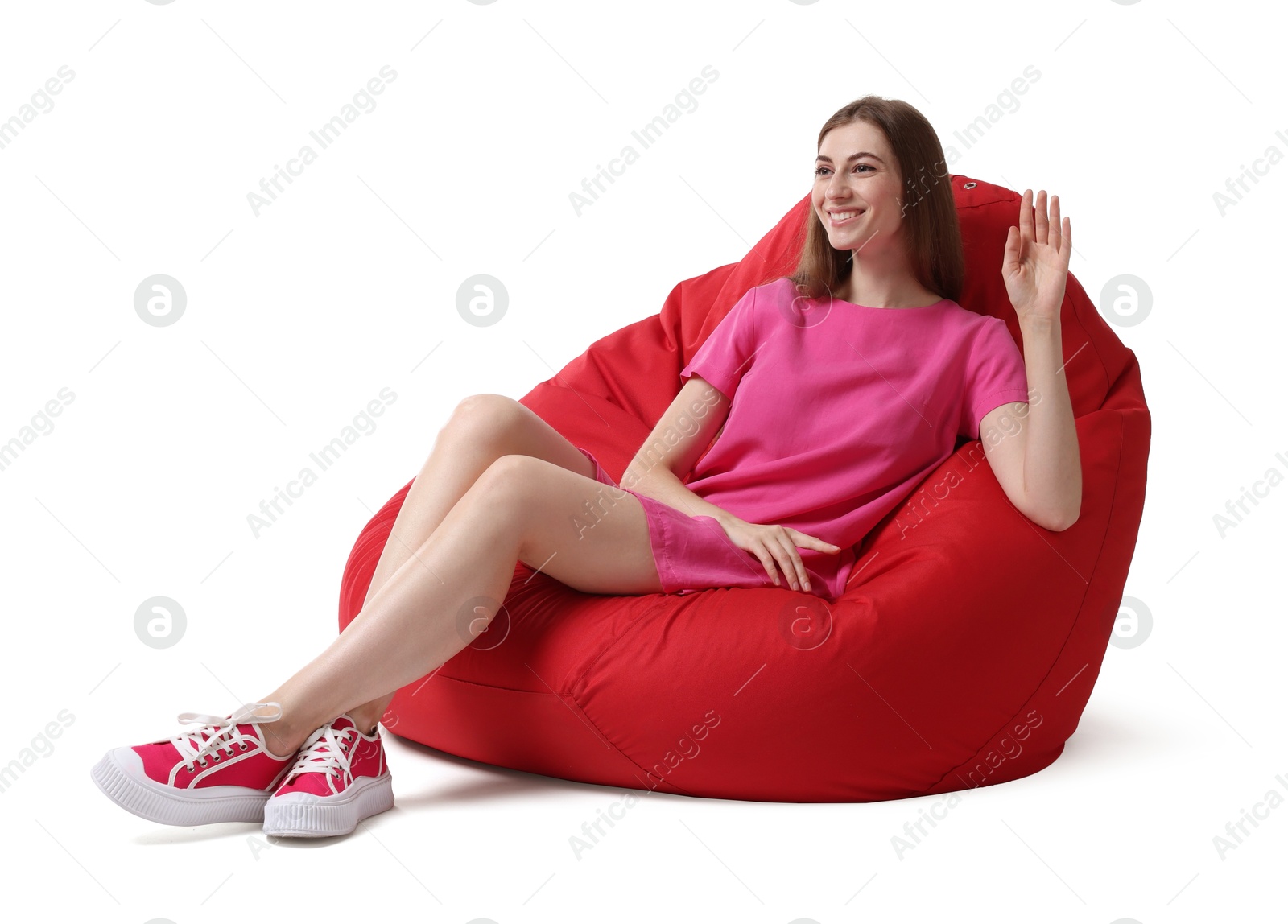 Photo of Smiling woman sitting on red bean bag chair against white background