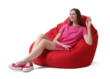 Smiling woman sitting on red bean bag chair against white background