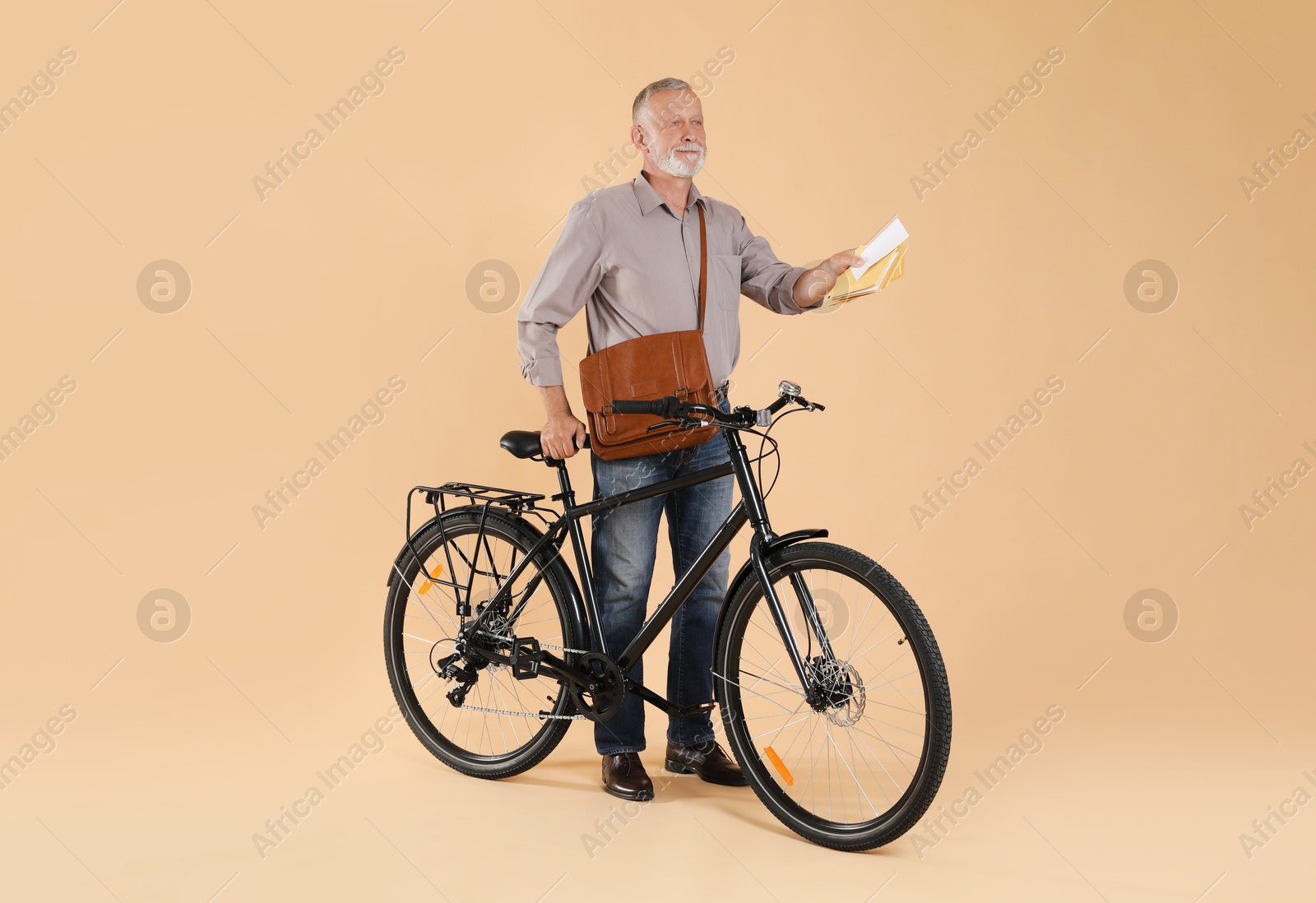 Photo of Postman with bicycle delivering letters on beige background