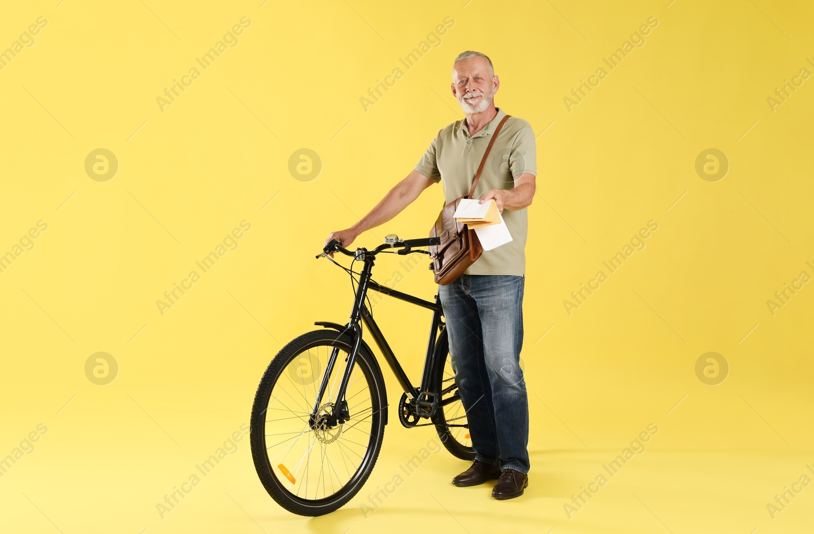 Photo of Postman with bicycle delivering letters on yellow background