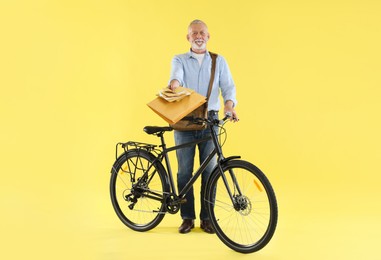 Postman with bicycle delivering letters on yellow background