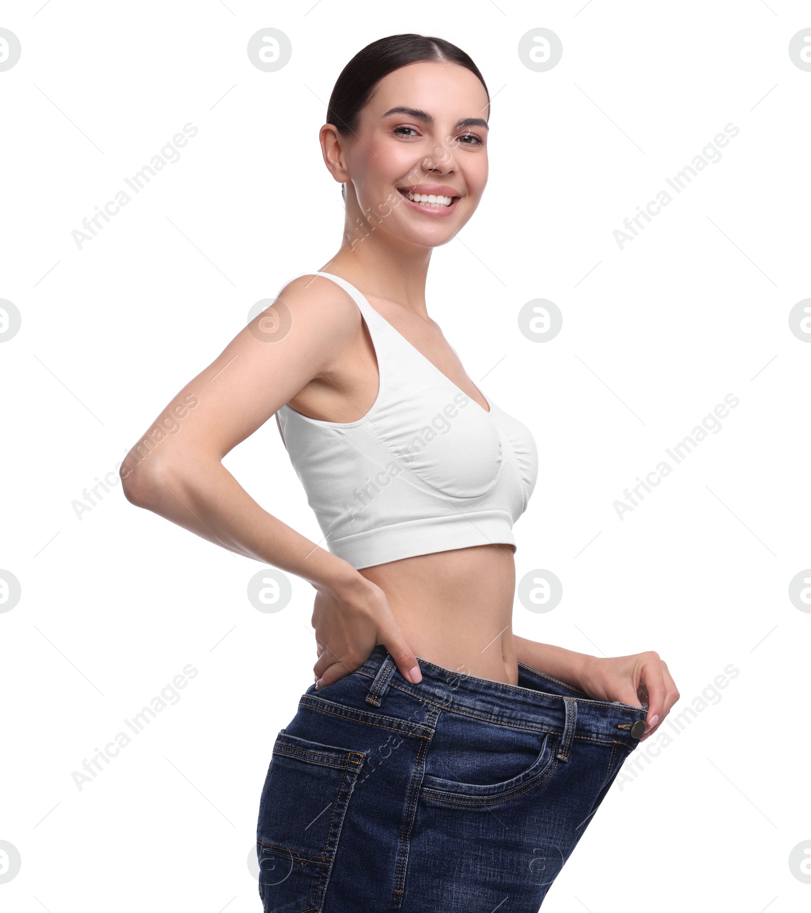 Photo of Diet and weight loss concept. Happy young woman in big jeans showing her slim body on white background