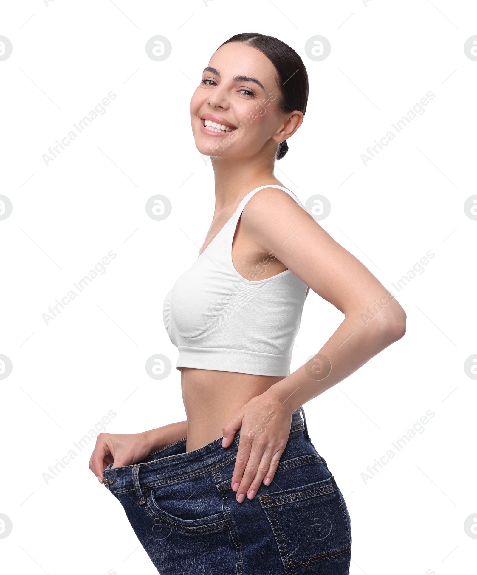 Photo of Diet and weight loss concept. Happy young woman in big jeans showing her slim body on white background