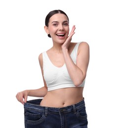 Photo of Diet and weight loss concept. Happy young woman in big jeans showing her slim body on white background