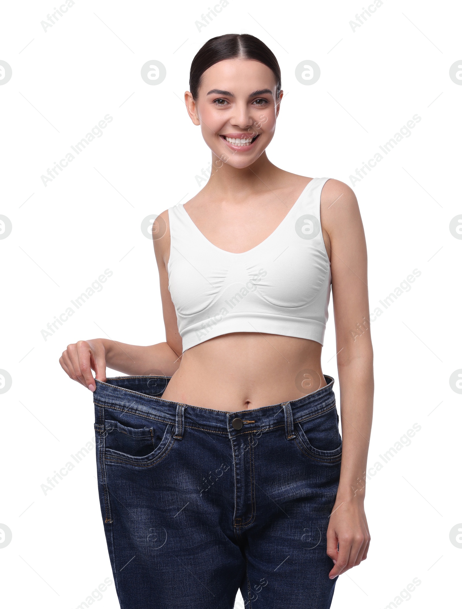 Photo of Diet and weight loss concept. Happy young woman in big jeans showing her slim body on white background