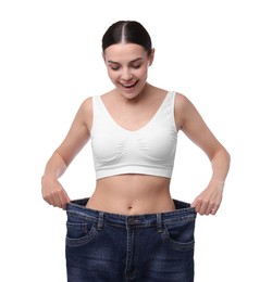 Photo of Diet and weight loss concept. Happy young woman in big jeans showing her slim body on white background