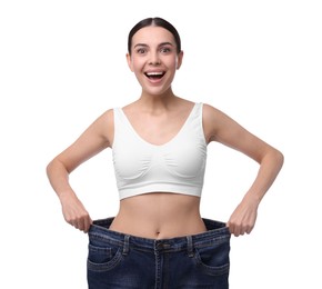 Photo of Diet and weight loss concept. Happy young woman in big jeans showing her slim body on white background