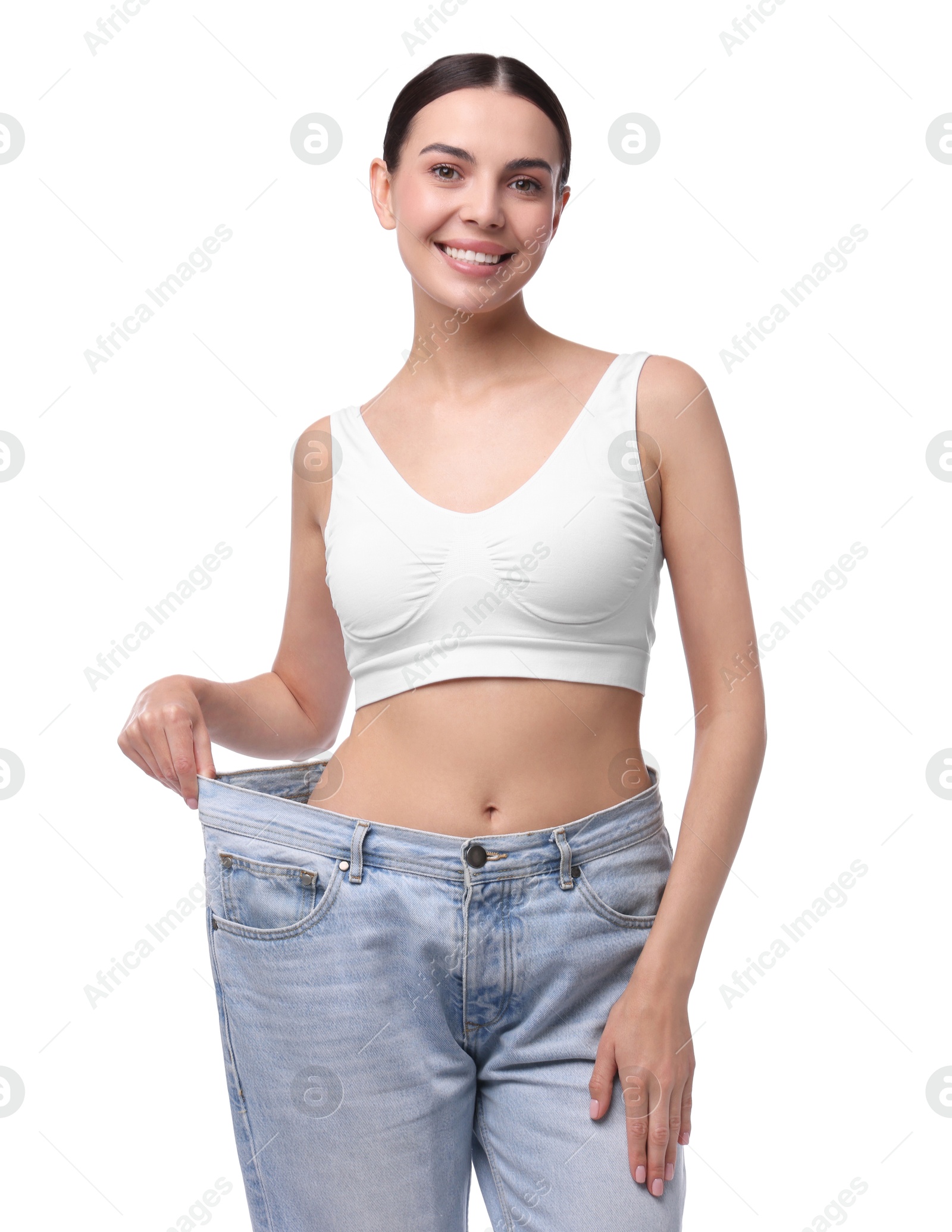 Photo of Diet and weight loss concept. Happy young woman in big jeans showing her slim body on white background