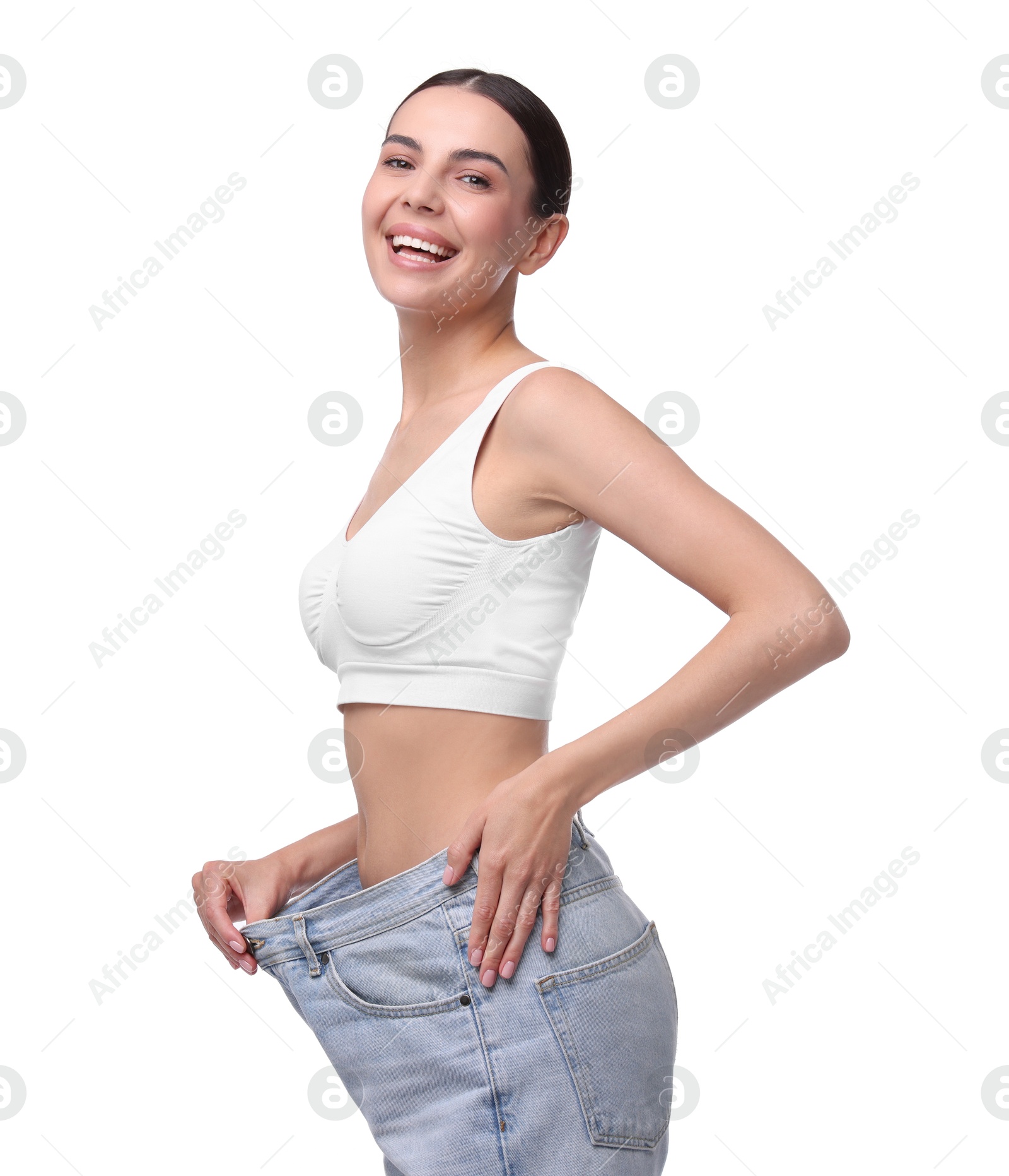 Photo of Diet and weight loss concept. Happy young woman in big jeans showing her slim body on white background