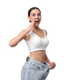 Photo of Diet and weight loss concept. Happy young woman in big jeans showing her slim body on white background