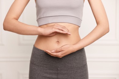 Healthy digestion. Woman holding something near her belly indoors, closeup