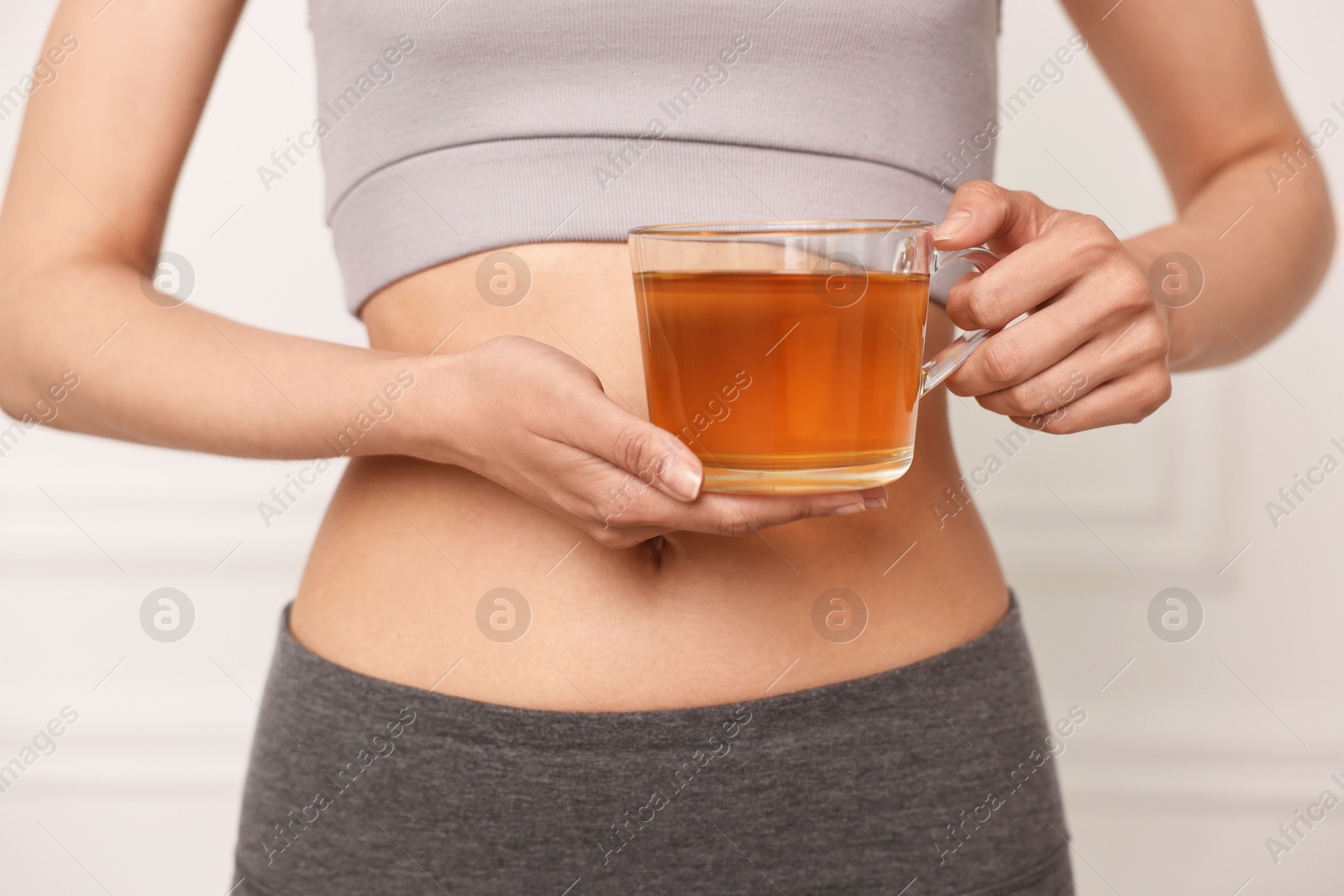 Photo of Weight loss concept. Woman with cup of diet tea near white wall, closeup