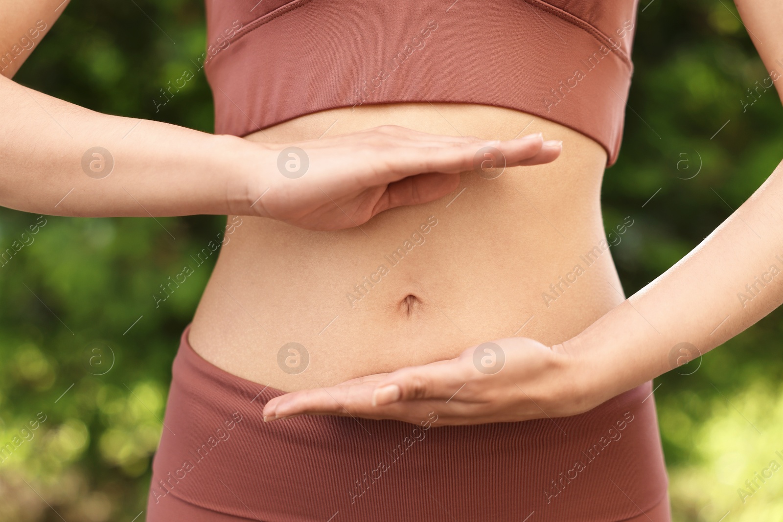 Photo of Healthy digestion. Woman holding something near her belly outdoors, closeup