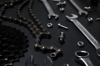 Different bicycle components and tools on dark gray textured background, closeup