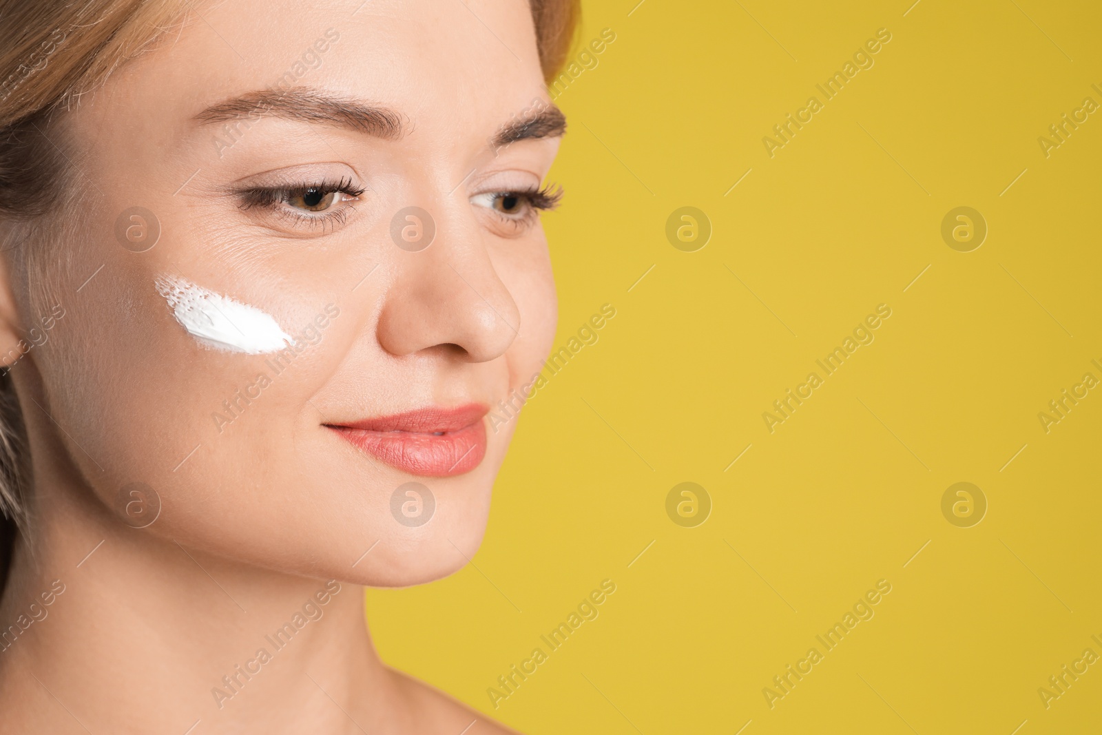 Photo of Beautiful woman with cream on her face against olive background, closeup. Space for text