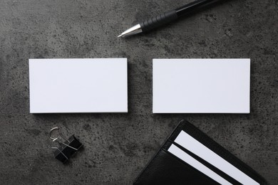 Photo of Leather card holder with blank business cards, pen and binder clip on grey textured table, flat lay. Mockup for design