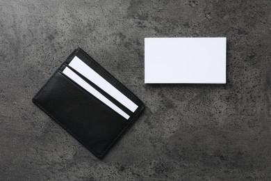 Photo of Leather card holder with blank business cards on grey textured table, flat lay. Mockup for design