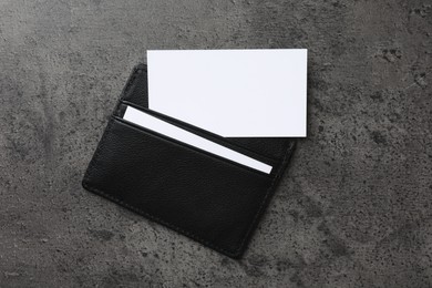 Photo of Leather card holder with blank business cards on grey textured table, top view. Mockup for design