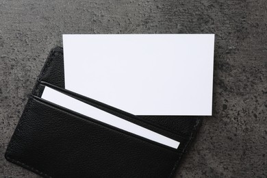 Leather card holder with blank business cards on grey textured table, top view. Mockup for design