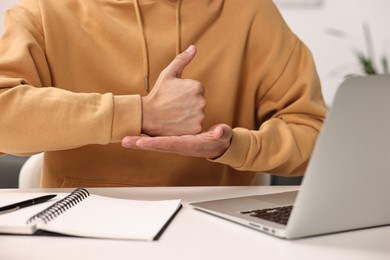 Photo of Young man using sign language during video call indoors, closeup