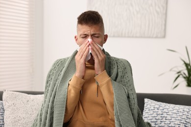 Cold symptom. Young man with runny nose at home