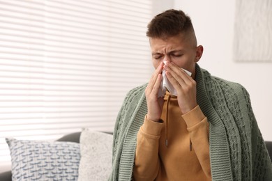 Cold symptom. Young man with runny nose at home