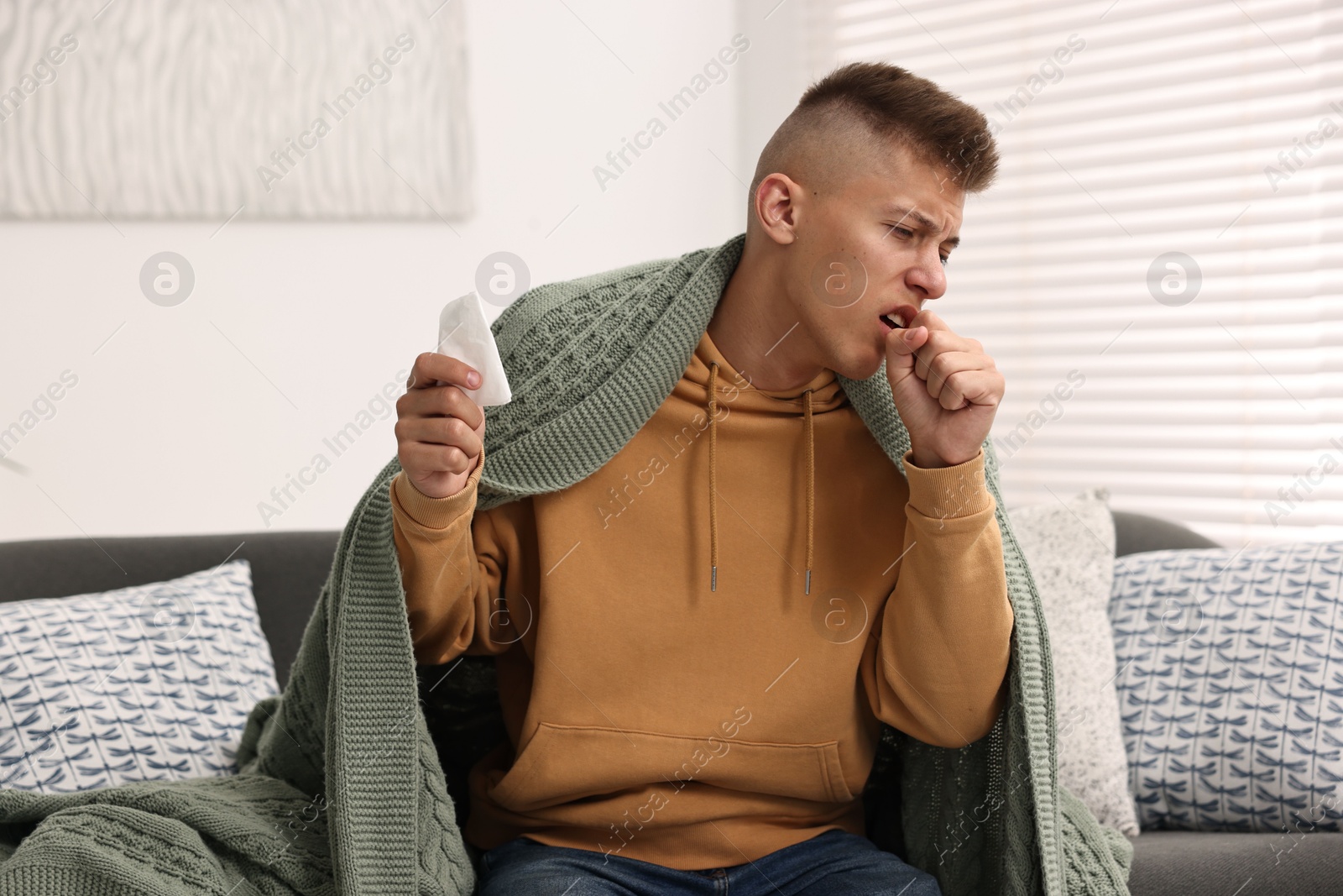 Photo of Cold symptom. Young man coughing at home