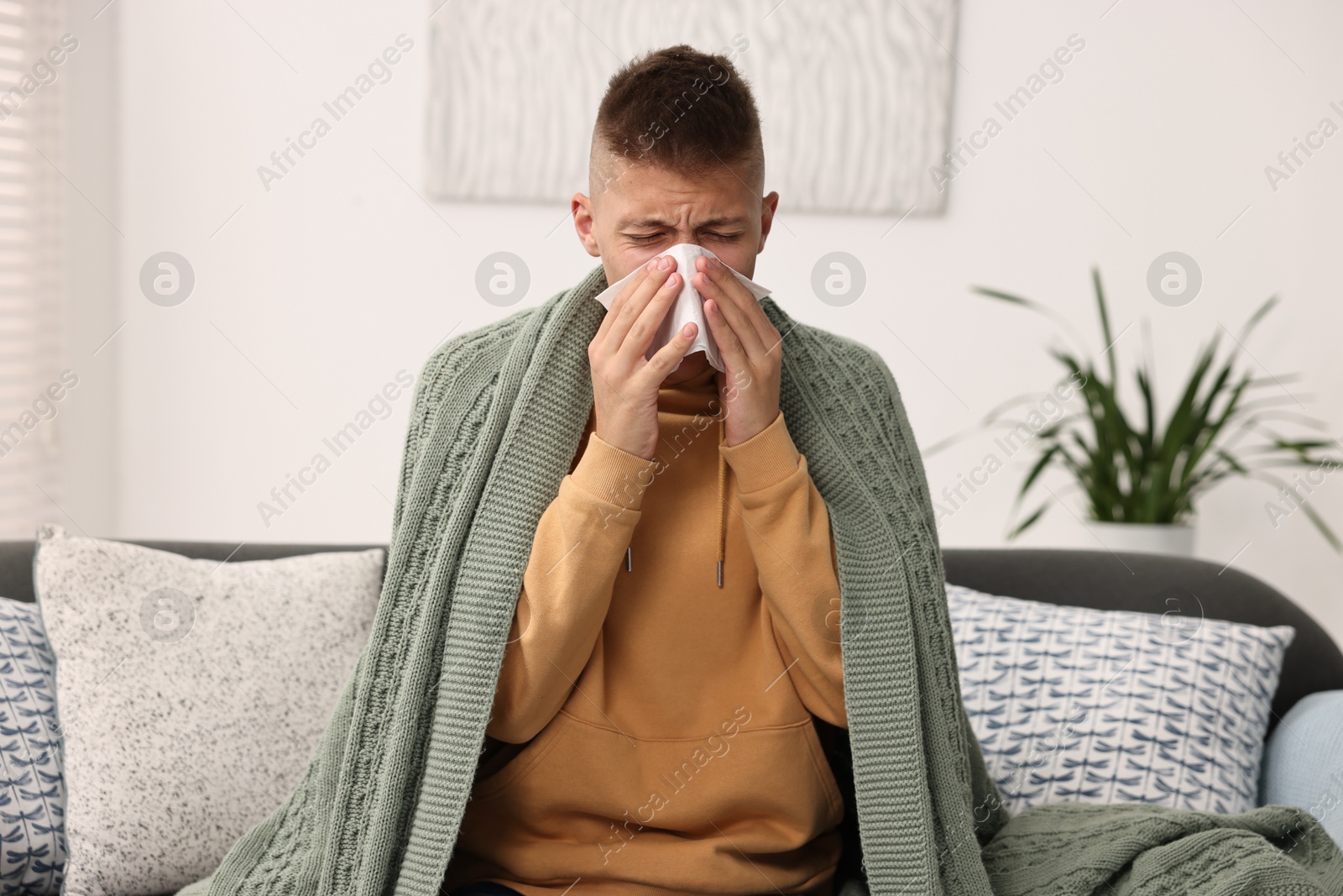 Photo of Cold symptom. Young man with runny nose at home