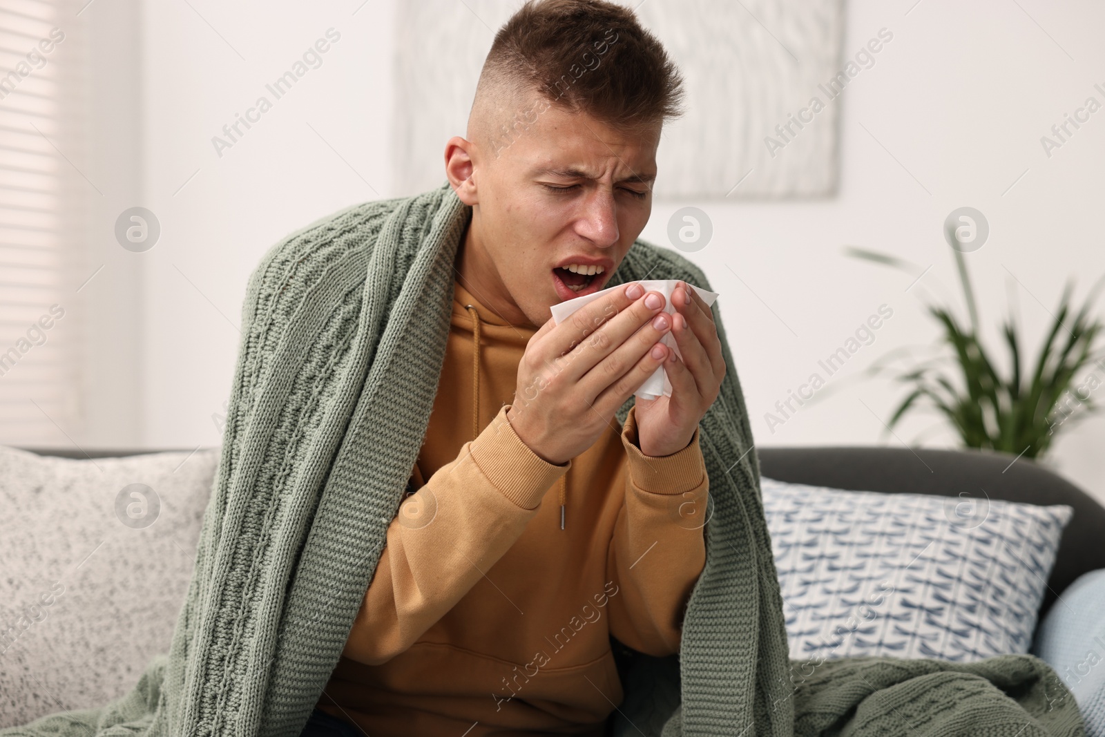 Photo of Cold symptom. Young man coughing at home