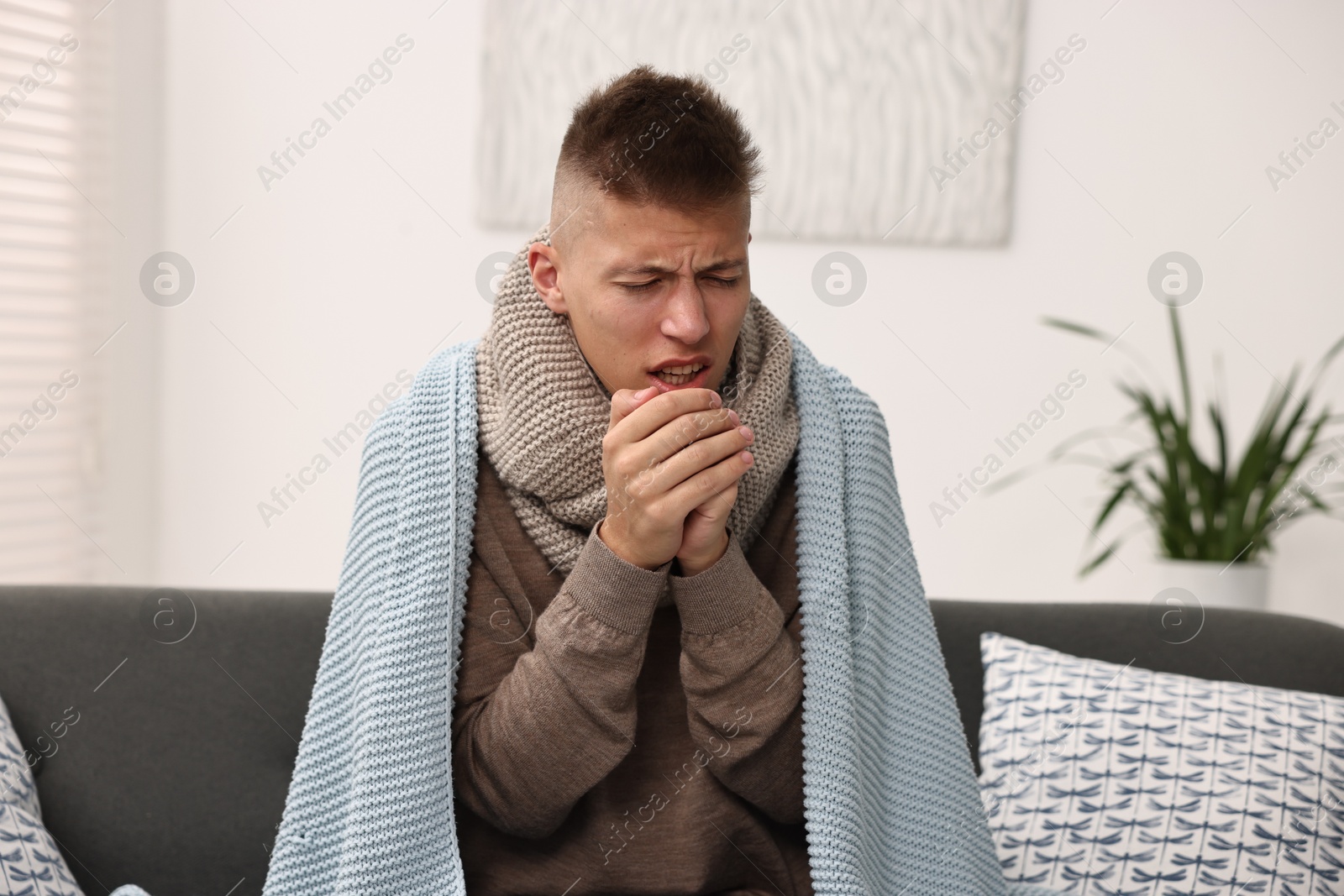 Photo of Cold symptom. Young man coughing at home