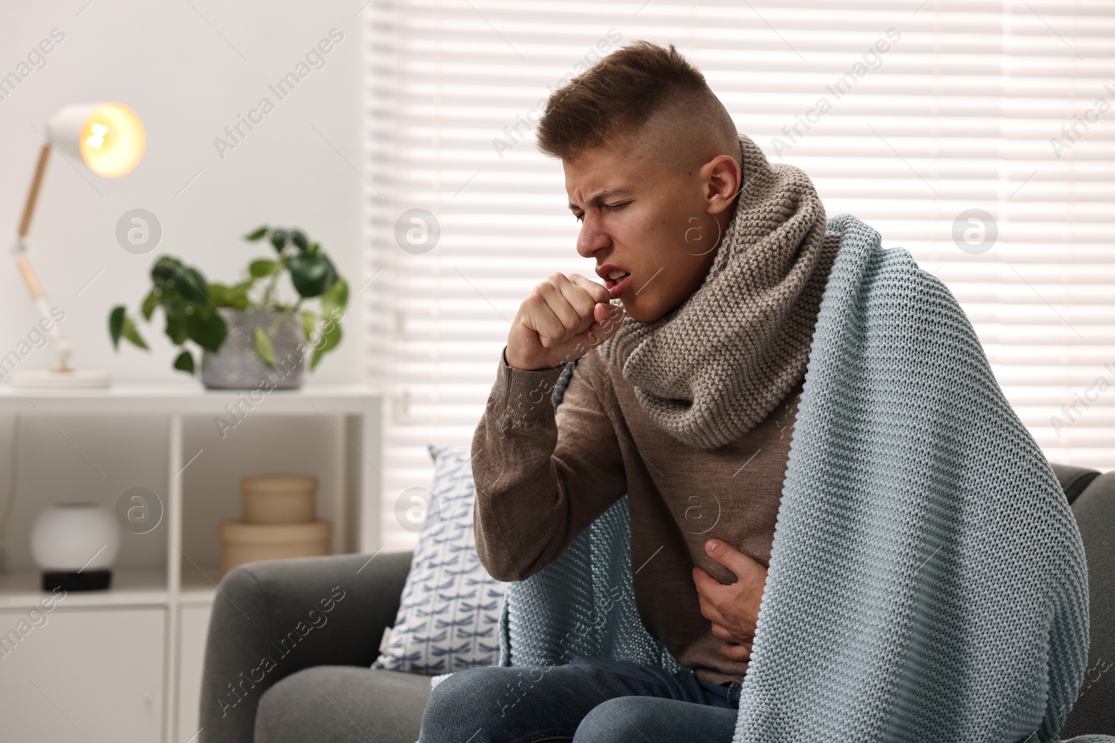 Photo of Cold symptom. Young man coughing at home