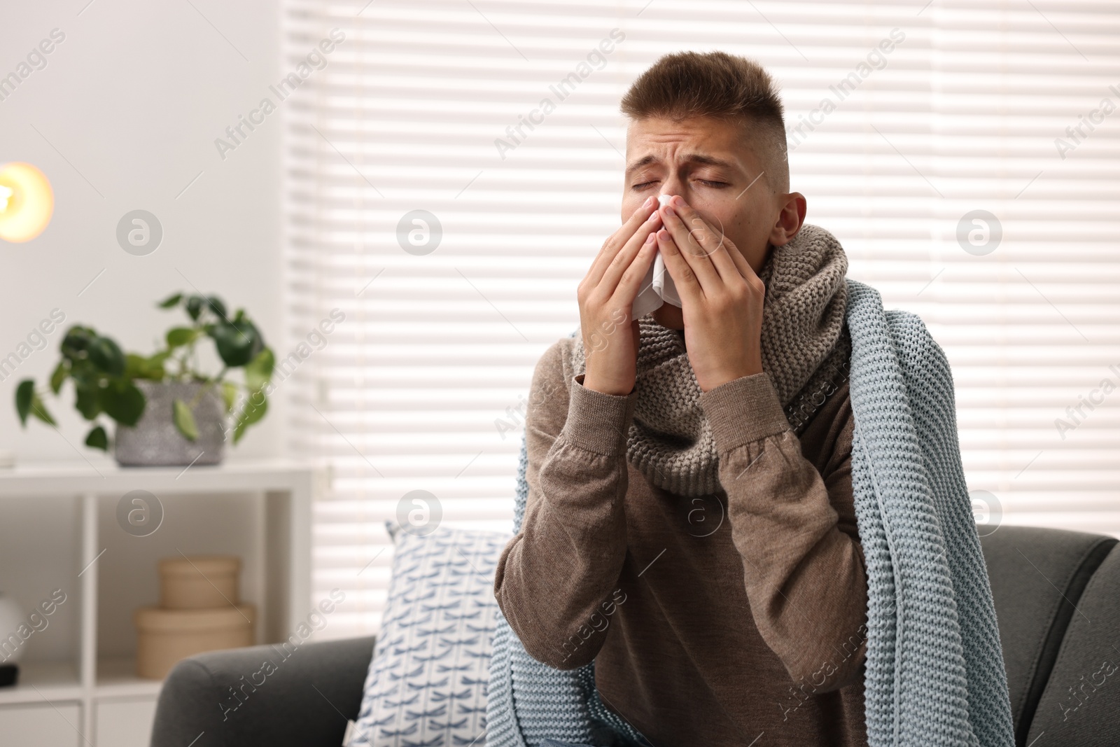 Photo of Cold symptom. Young man with runny nose at home