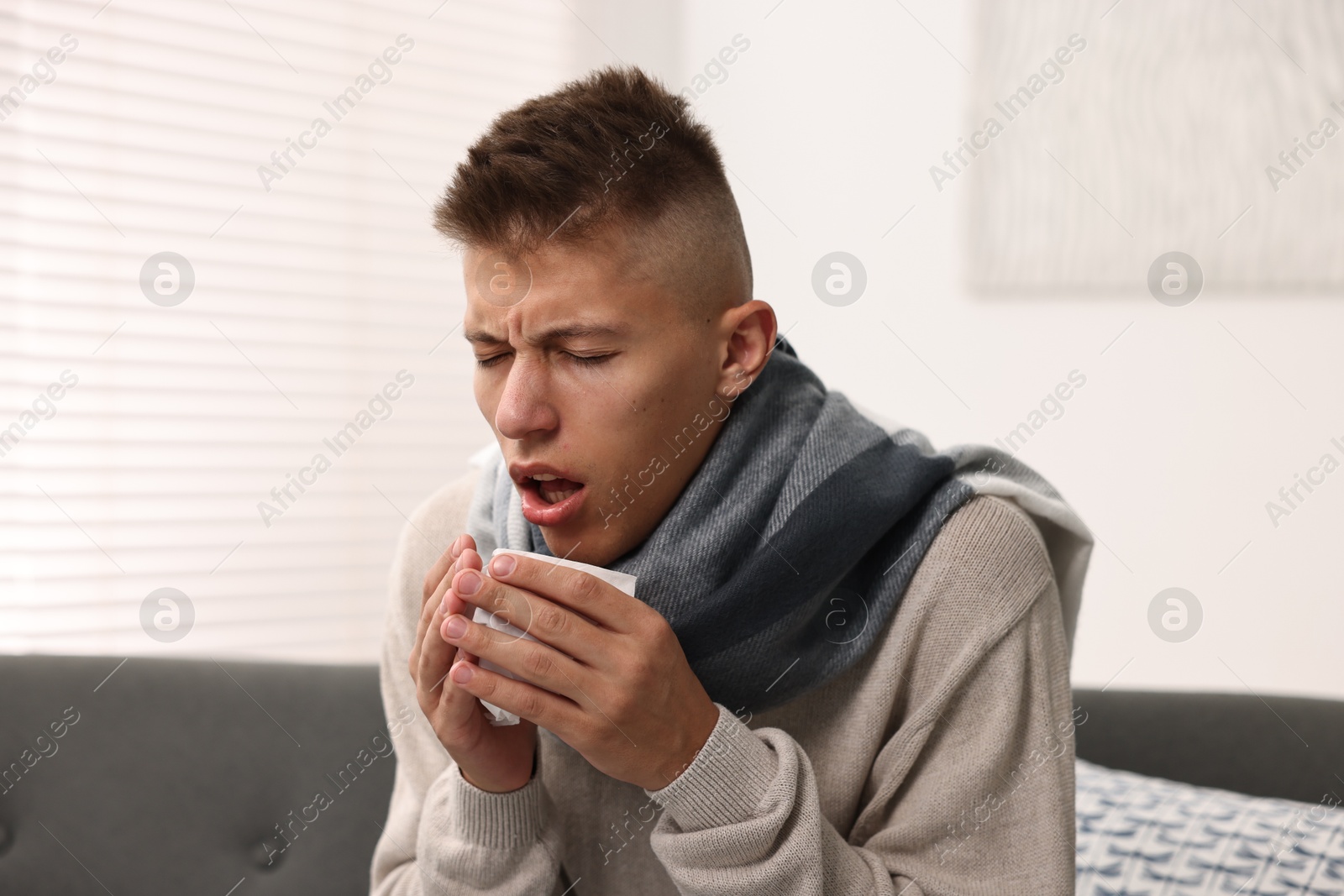 Photo of Cold symptom. Young man coughing at home