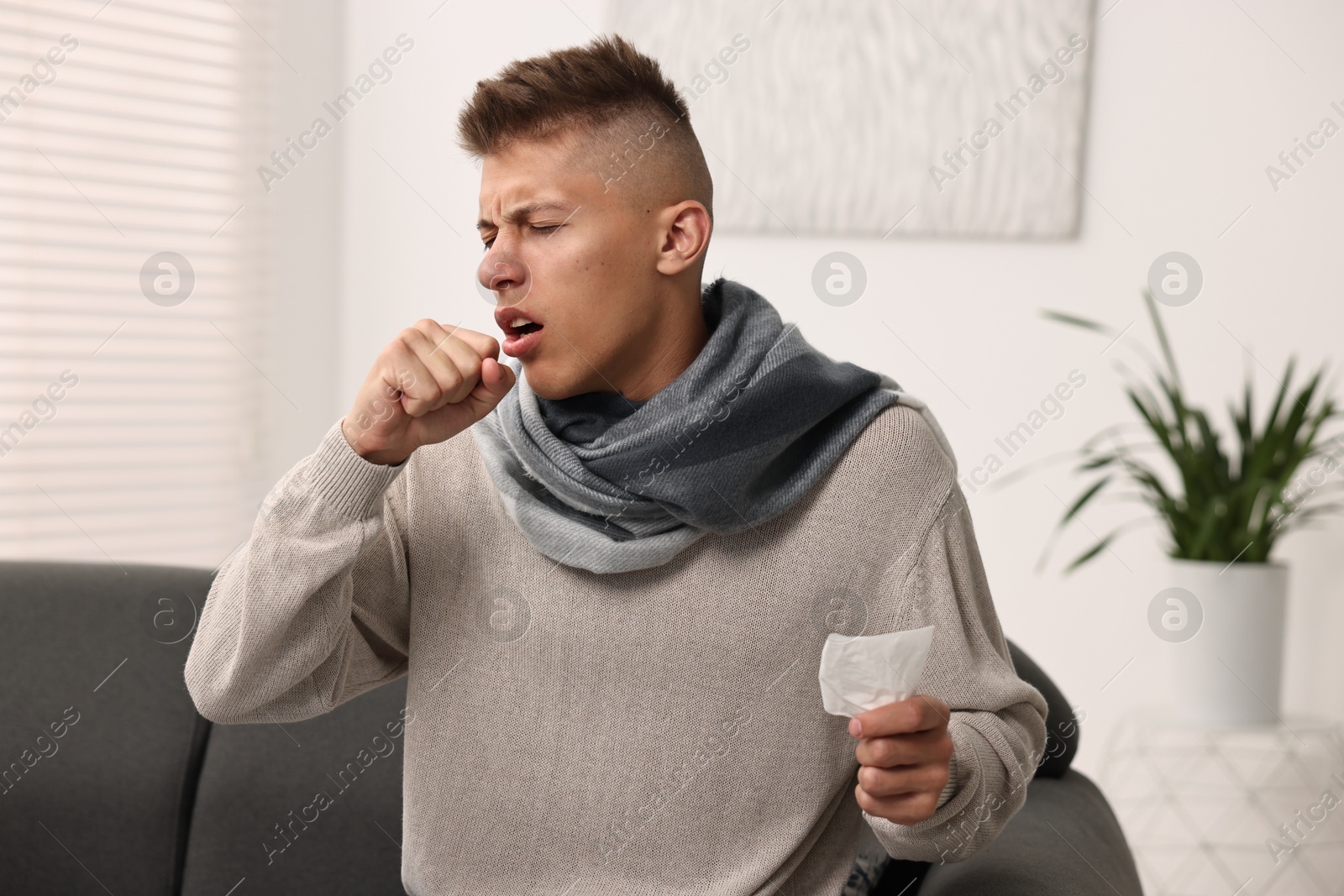 Photo of Cold symptom. Young man coughing at home