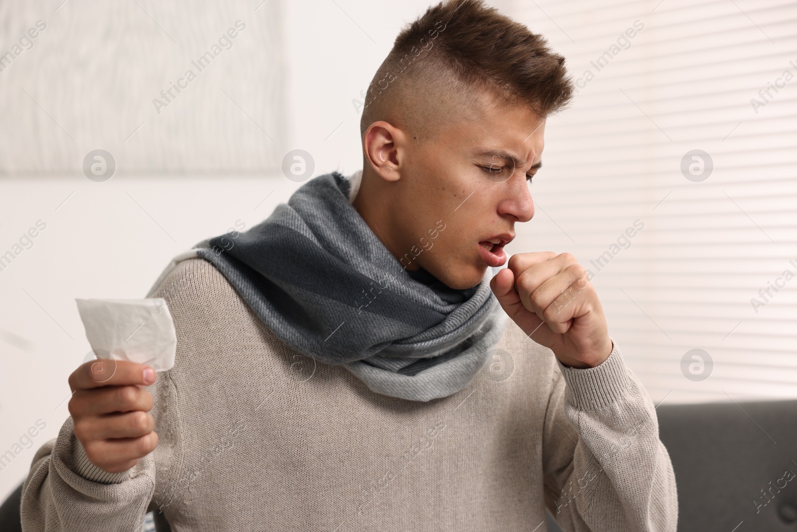 Photo of Cold symptom. Young man coughing at home